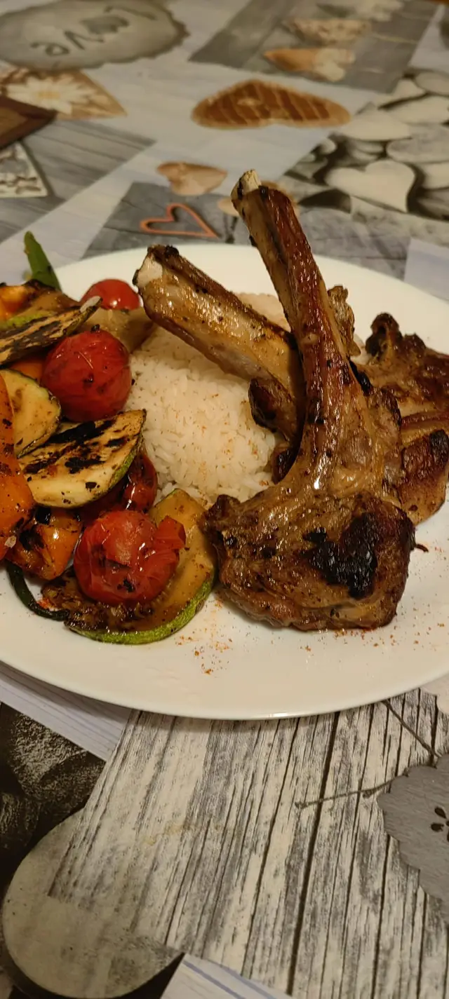 Cotlete la gratar, cu orez si legume, servite pe farfurie