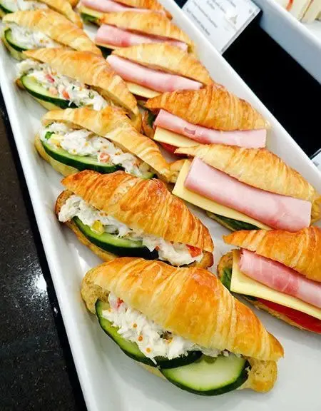 Croissante umplute cu crema de branza, castravete si sunca, pe platou alb