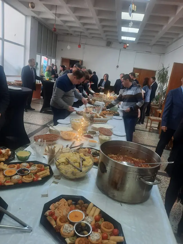 Invitati servindu-se de la bufetul montat intr-o sala de eveniment corporate