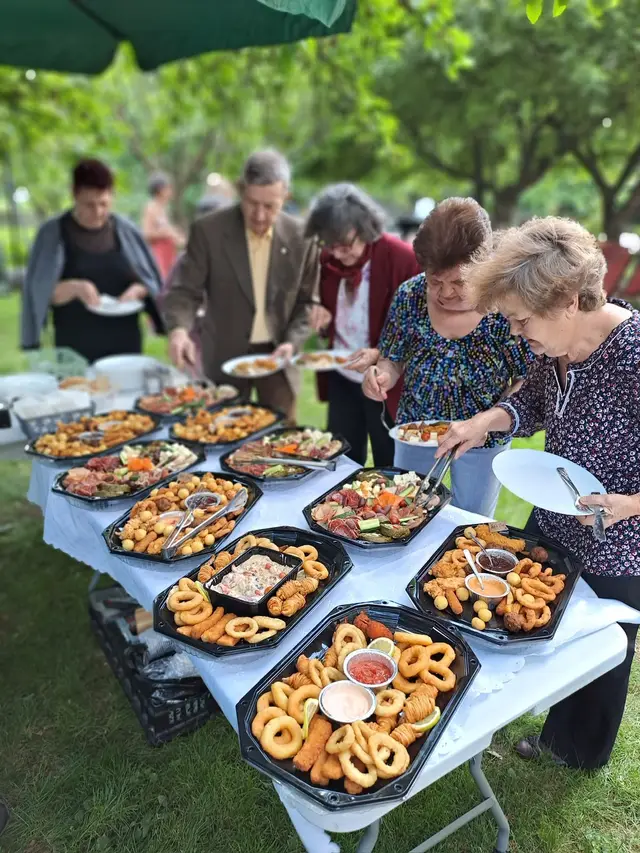 Invitati servindu-se de la platourile reci, la un eveniment in gradina